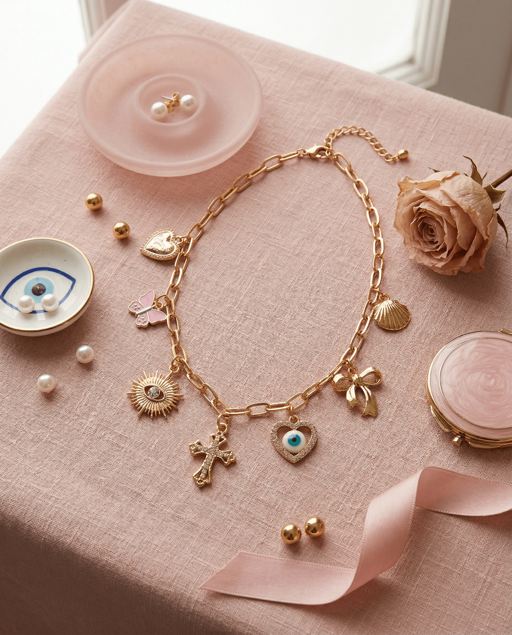 Feminine styled flat-lay of Frosted Feminine Love & Luck Charm Necklace with delicate gold charms